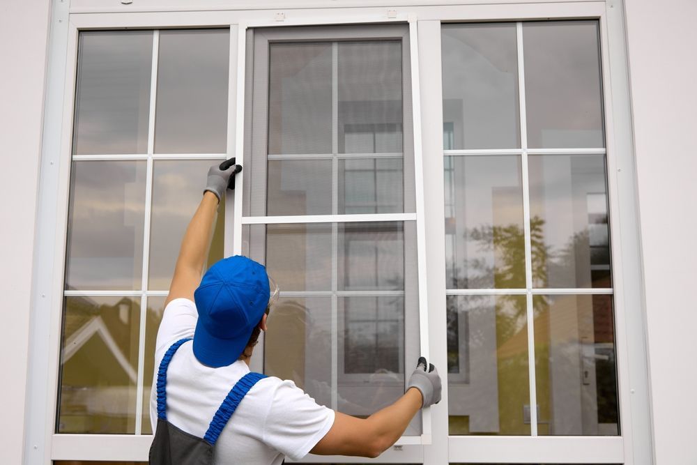 Worker cleaning a white window frame with a cloth and spray bottle