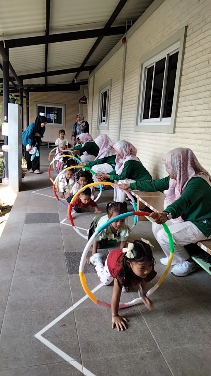 A group of children are playing with hula hoops in a hallway.