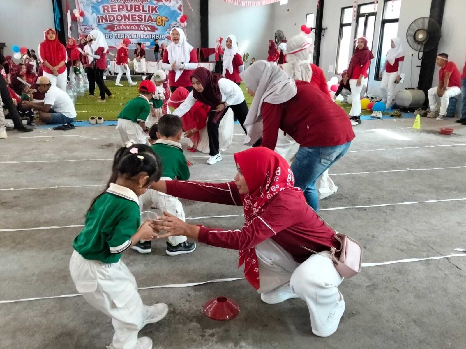 Children in red and white play a cone-toss game in a decorated indoor hall with balloons and banners.