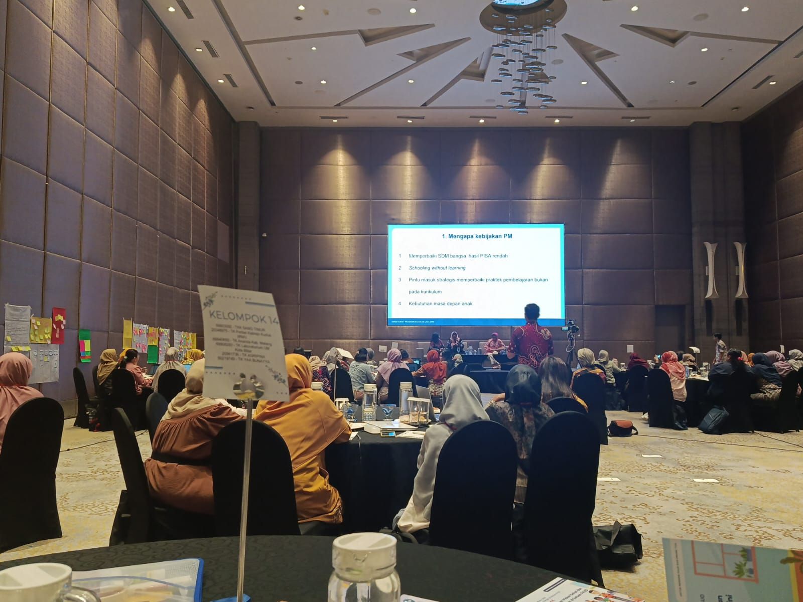 Conference audience seated in ballroom facing a presentation screen at the front