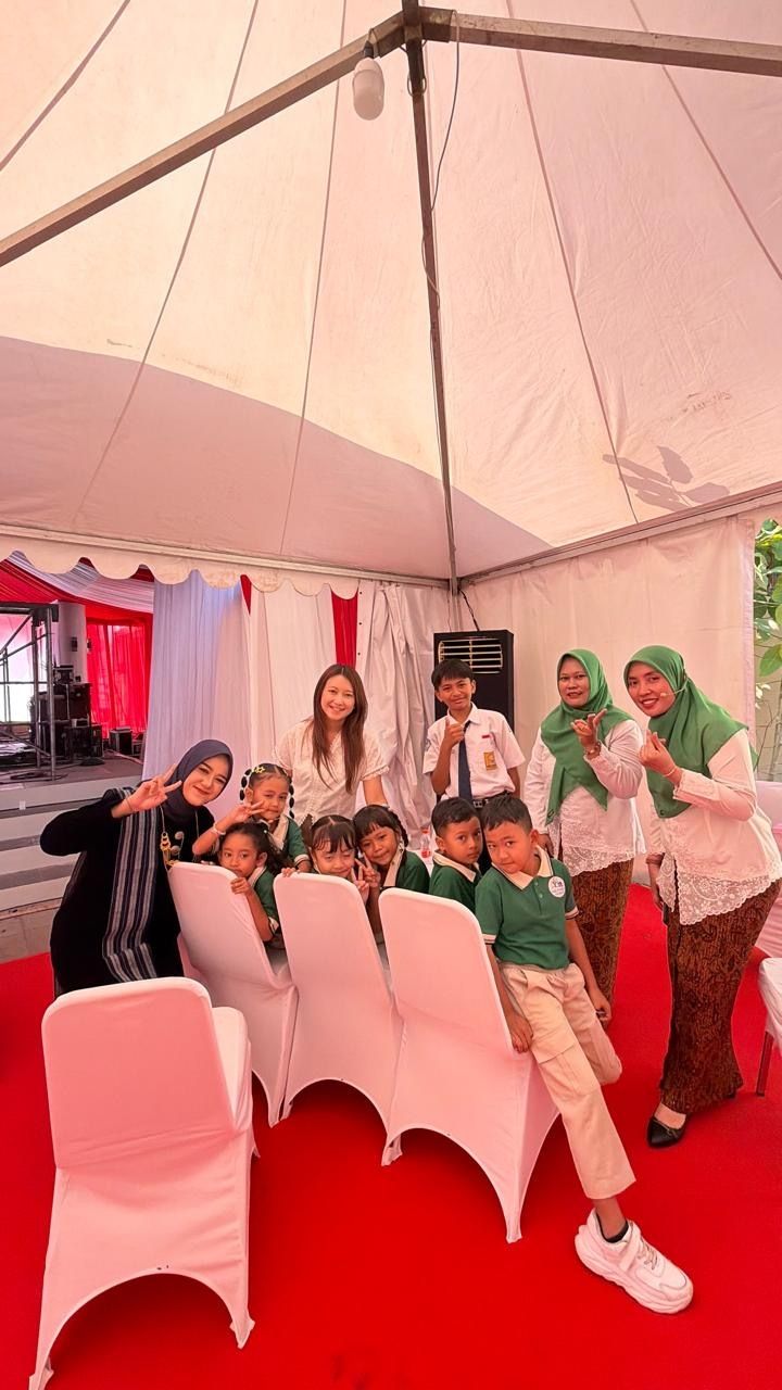 Group posing inside a white event tent with red carpet and white chairs, some making peace signs