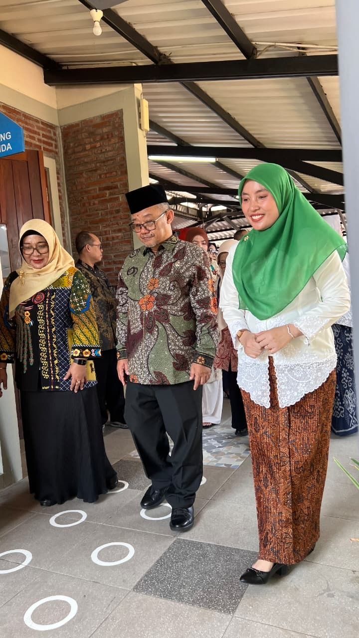 People standing together on a covered patio, including one in a green headscarf and patterned clothing.