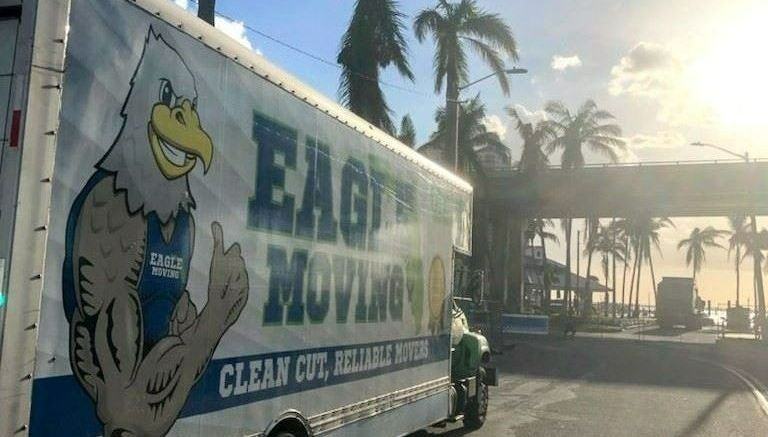 Eagle Moving box truck parked on a palm-lined road in Naples, FL