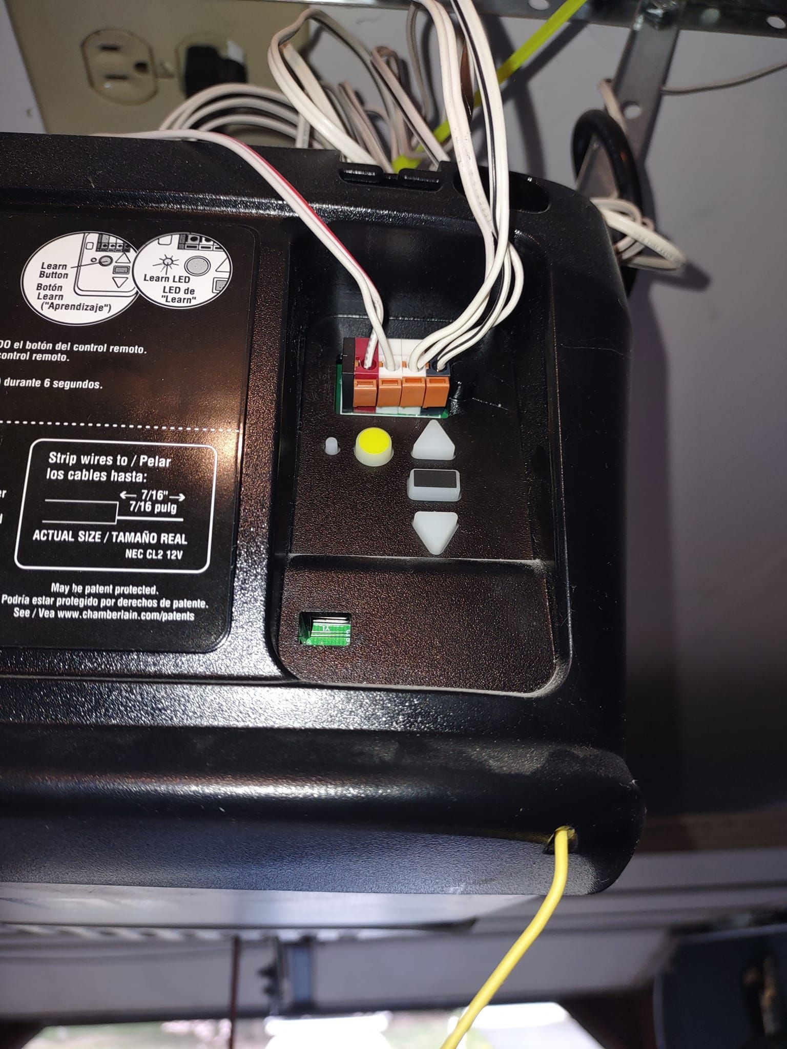 Close-up of a black electronic device with wires, buttons, and indicator lights on a shelf.