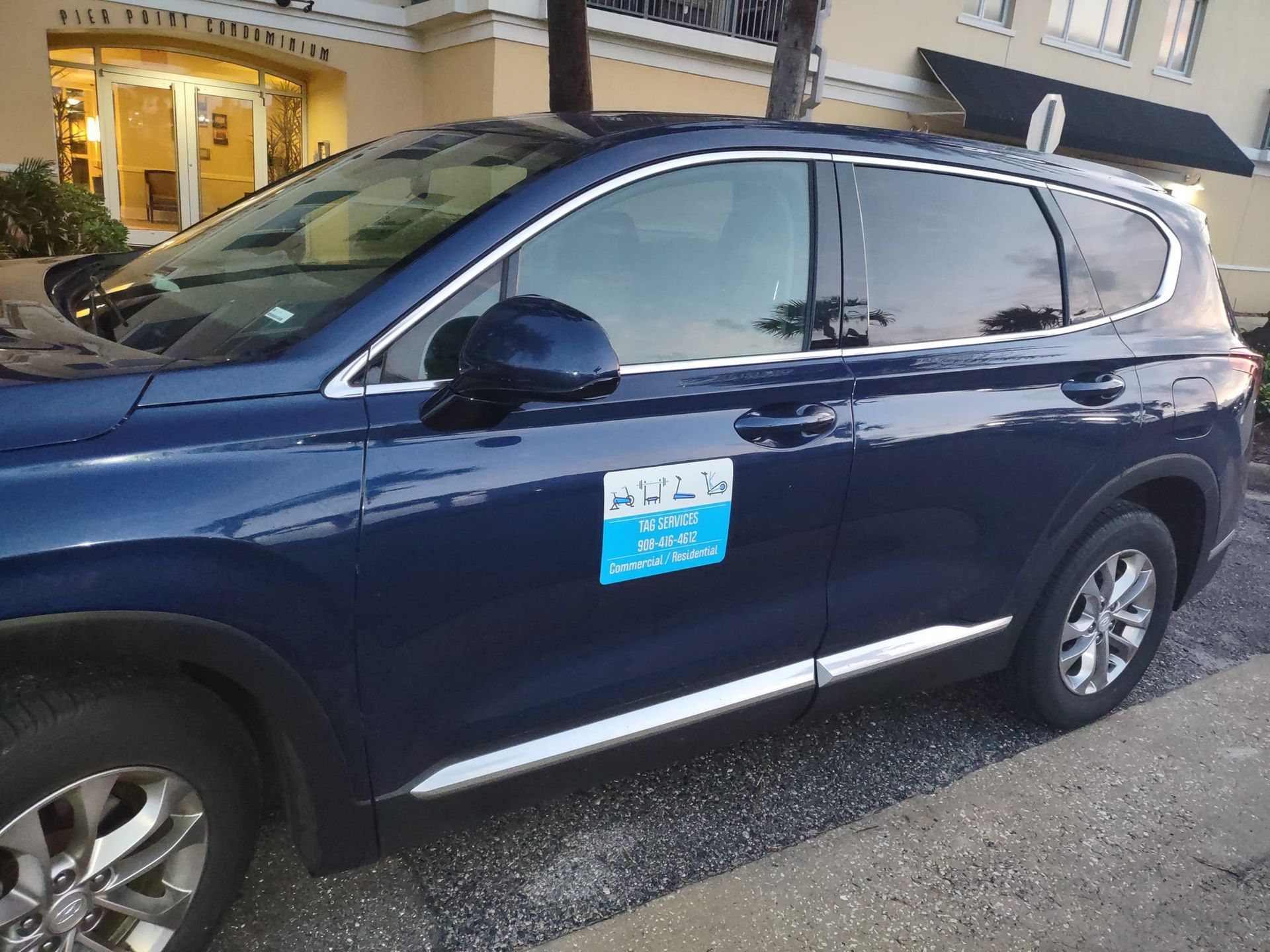 Dark blue SUV parked on a street in front of a building, with a blue sign on the door