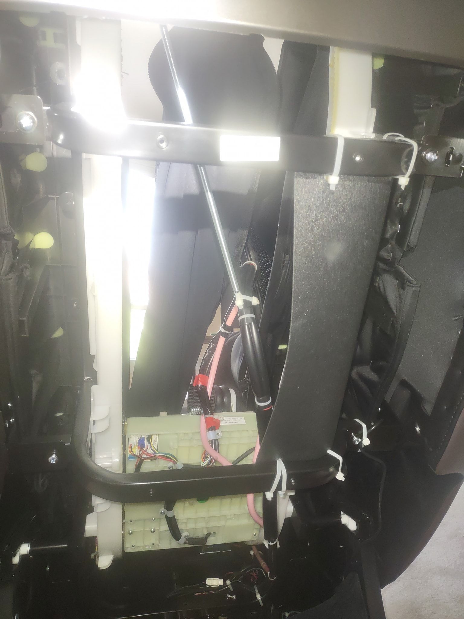 Interior of an electronic device with exposed wiring, metal frame, and black insulation panels.
