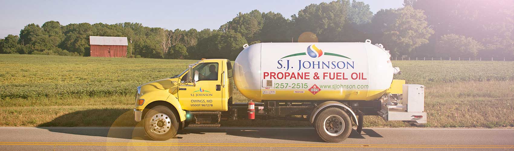 A yellow propane truck is parked on the side of the road.