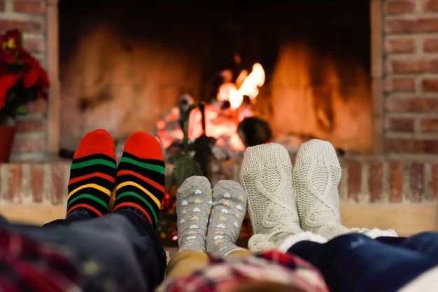 A family is laying in front of a fireplace wearing socks.
