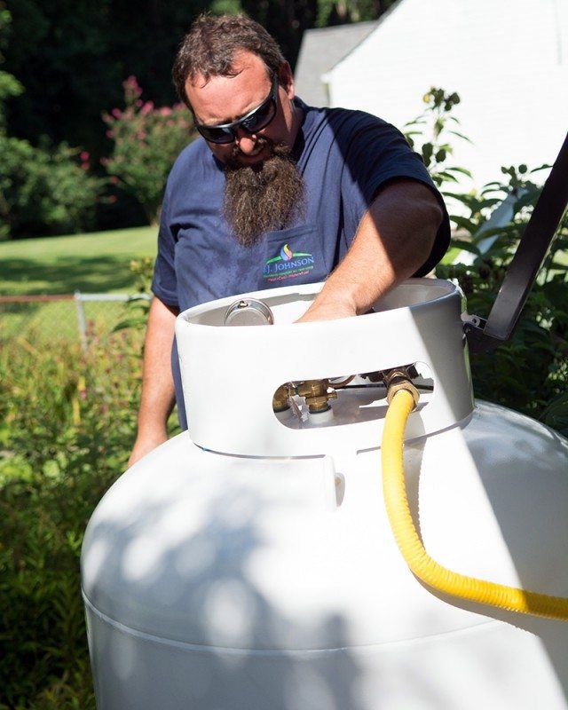 A man with a beard is working on a propane tank