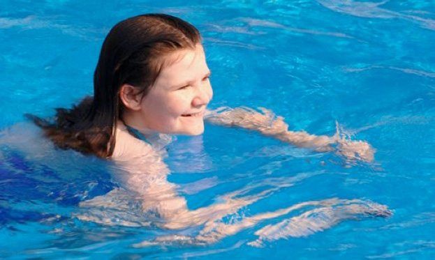 A young girl is swimming in a swimming pool.
