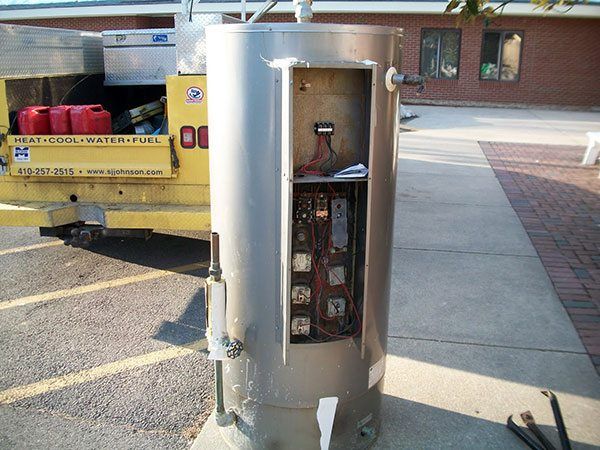 A stainless steel water heater is sitting on the sidewalk