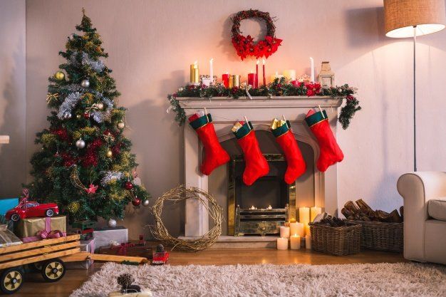 A living room decorated for christmas with a fireplace , christmas tree , and stockings hanging on the mantle.