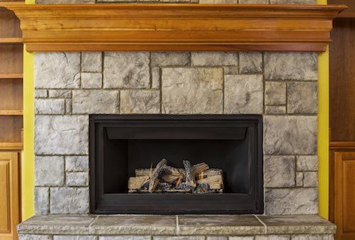 A stone fireplace with a wooden mantle in a living room.