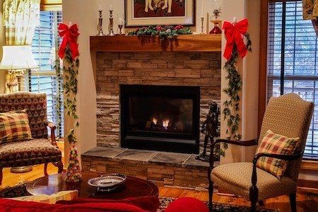 A living room with a gas fireplace and chairs decorated for christmas