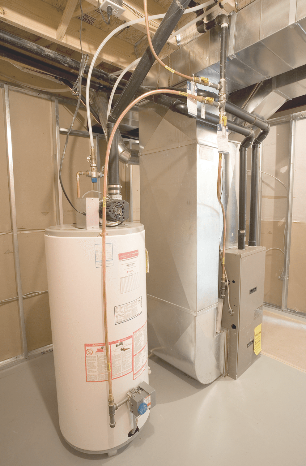 A water heater is sitting next to a furnace in a basement.