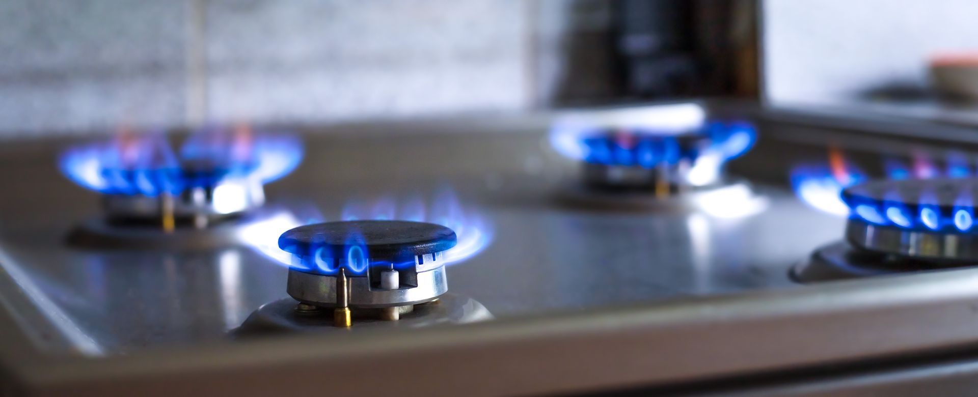 A close up of three gas burners on a stove with blue flames.