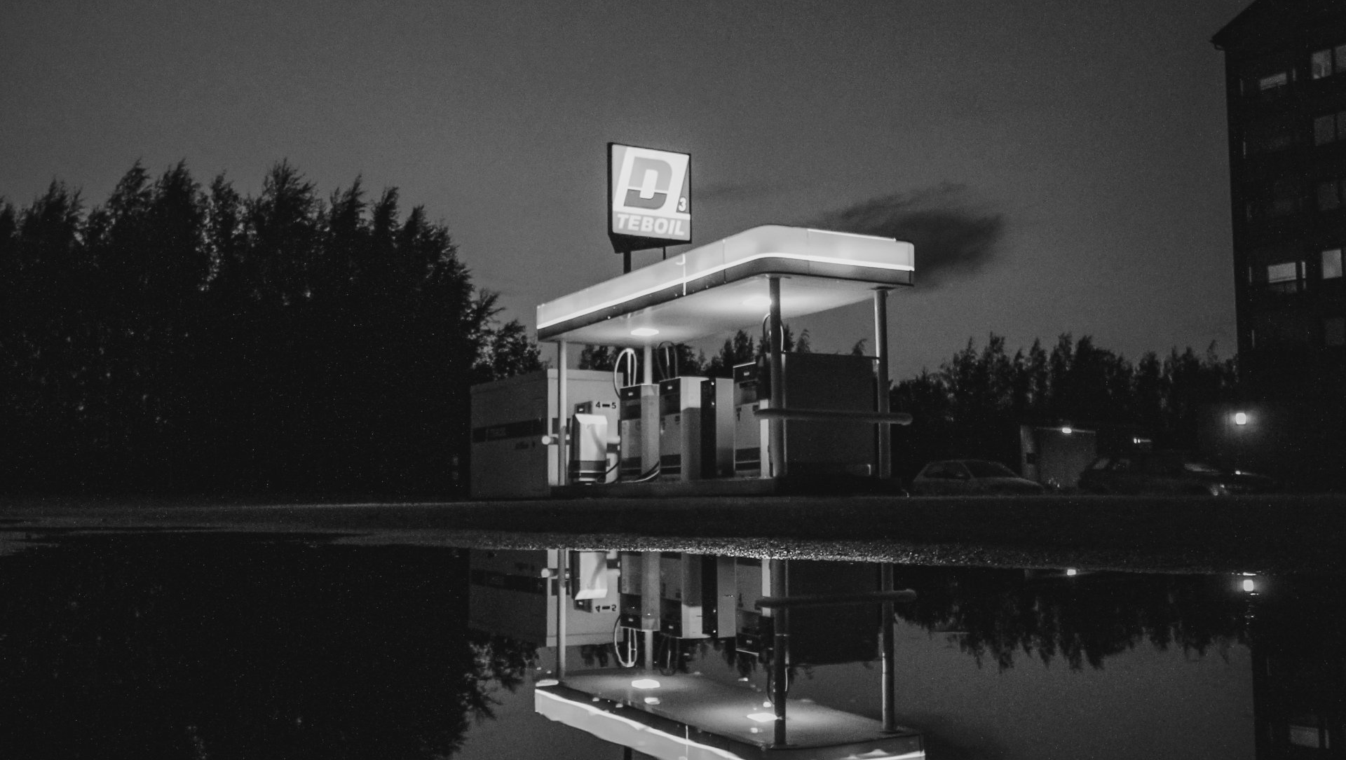 A black and white photo of a gas station at night.