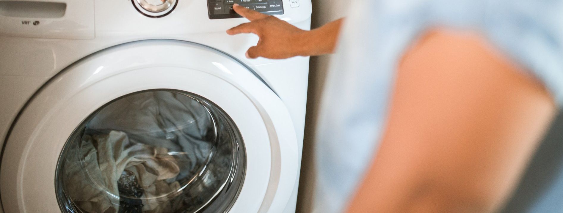 A person is pressing a button on a washing machine.