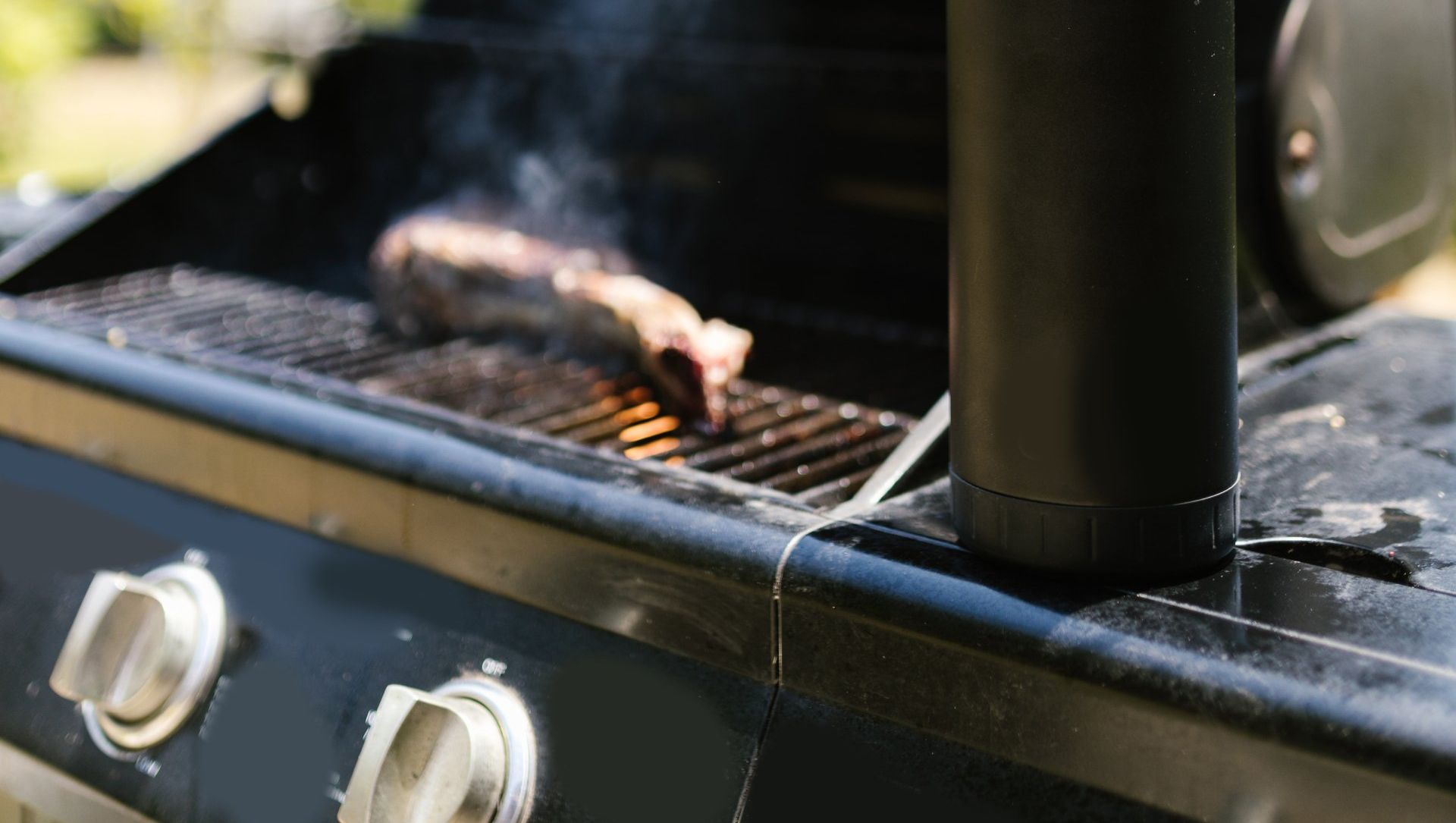 A steak is cooking on a grill with smoke coming out of it.