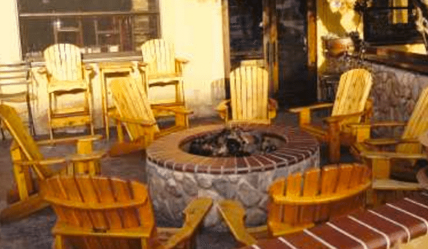 A fire pit surrounded by wooden chairs on a patio