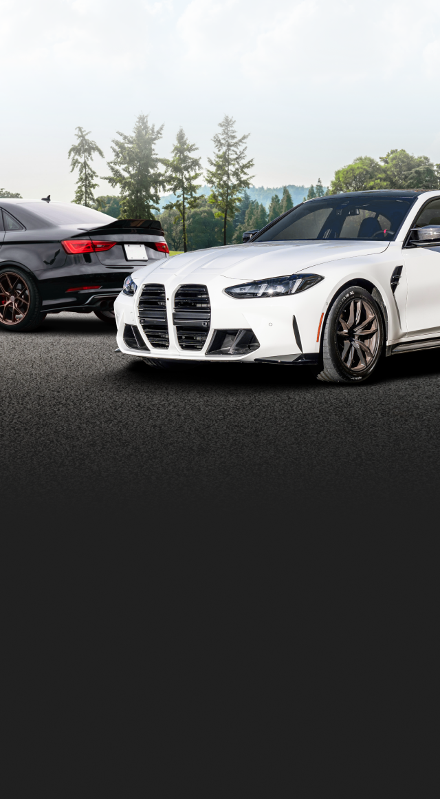White and black sports cars on a road with a mountain background | Ken's Import Service