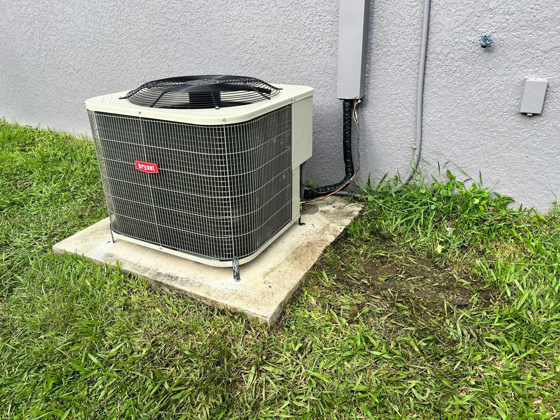 an air conditioner is sitting on top of a concrete platform in the grass .