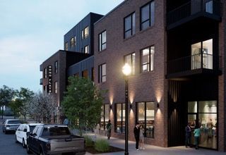 Modern apartment building at dusk with lit windows, parked cars, and people near the entrance