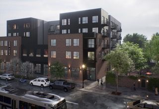 Modern brick apartment building at dusk with parked cars and trees along a wet street