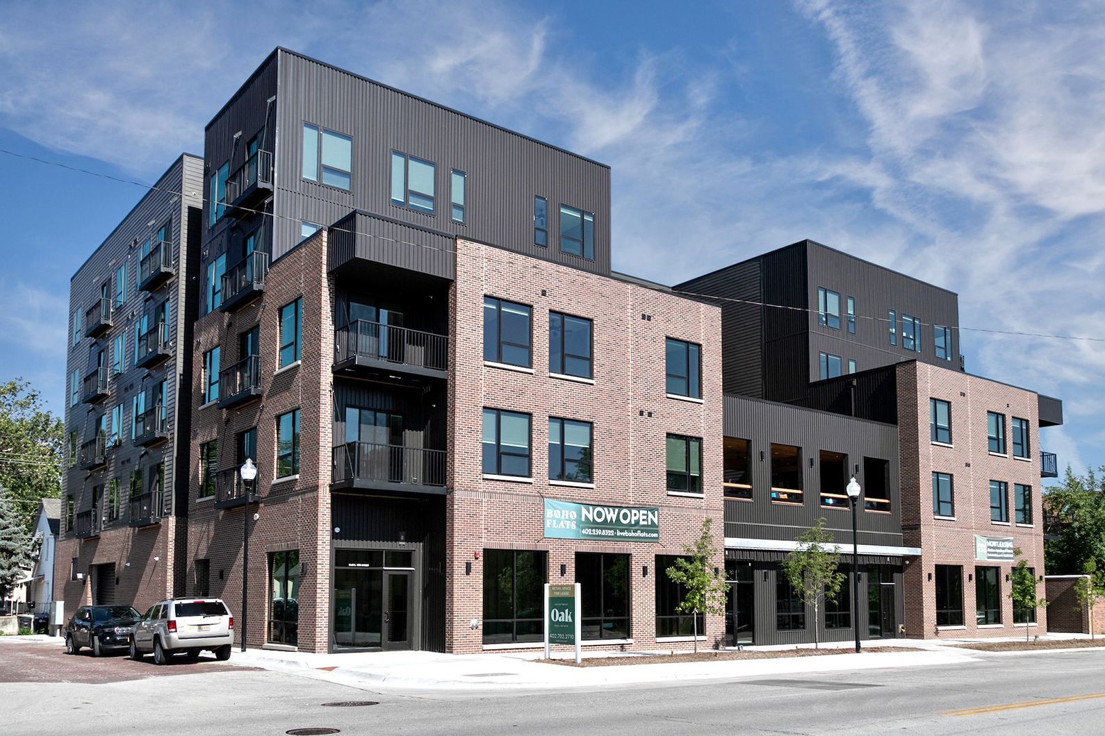 Modern brick-and-glass apartment building on a city street under a blue sky