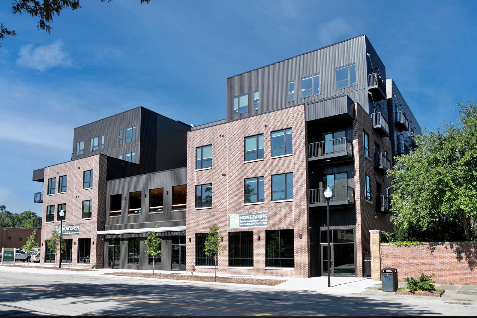 Modern brick-and-glass apartment building on a sunny street corner