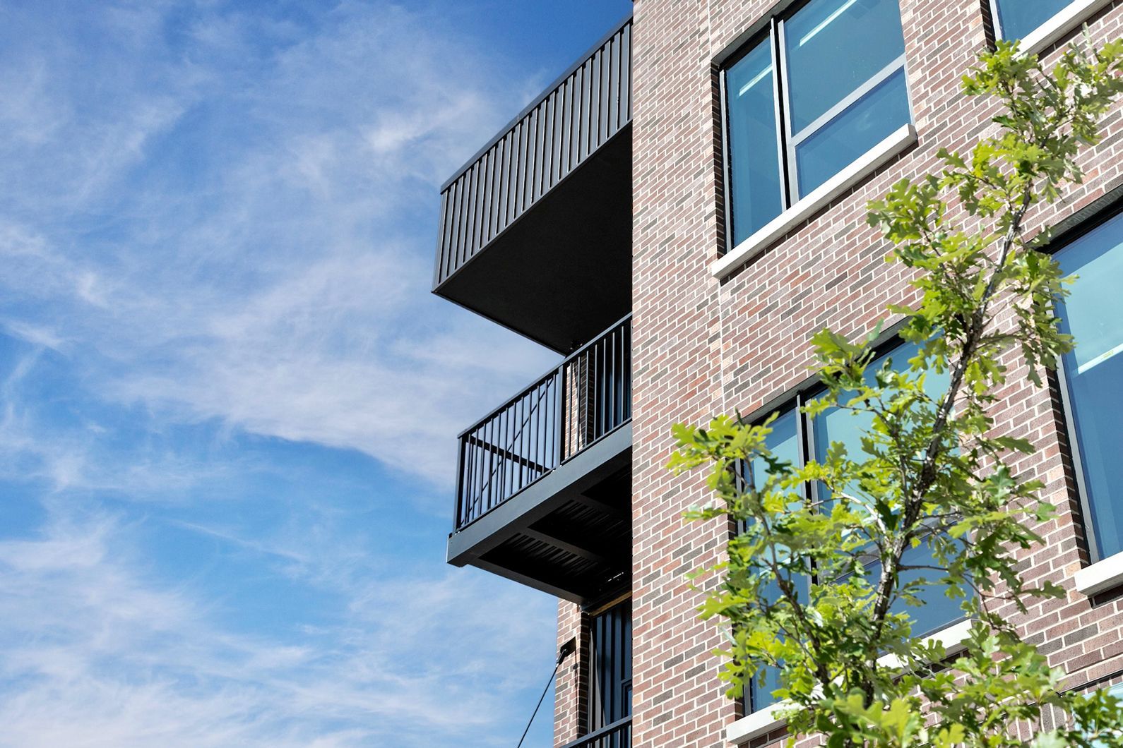 Modern brick apartment building with black balconies against a blue sky