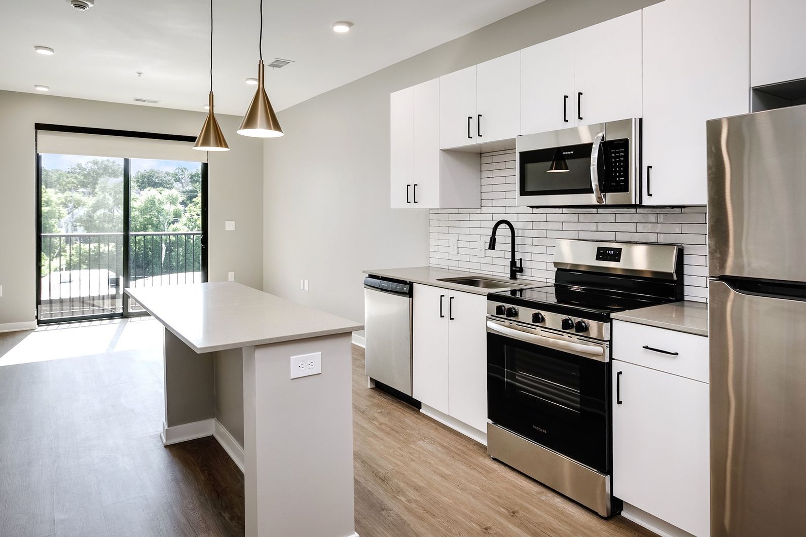 Bright modern kitchen with white cabinets, stainless appliances, island, and sliding glass doors to a patio