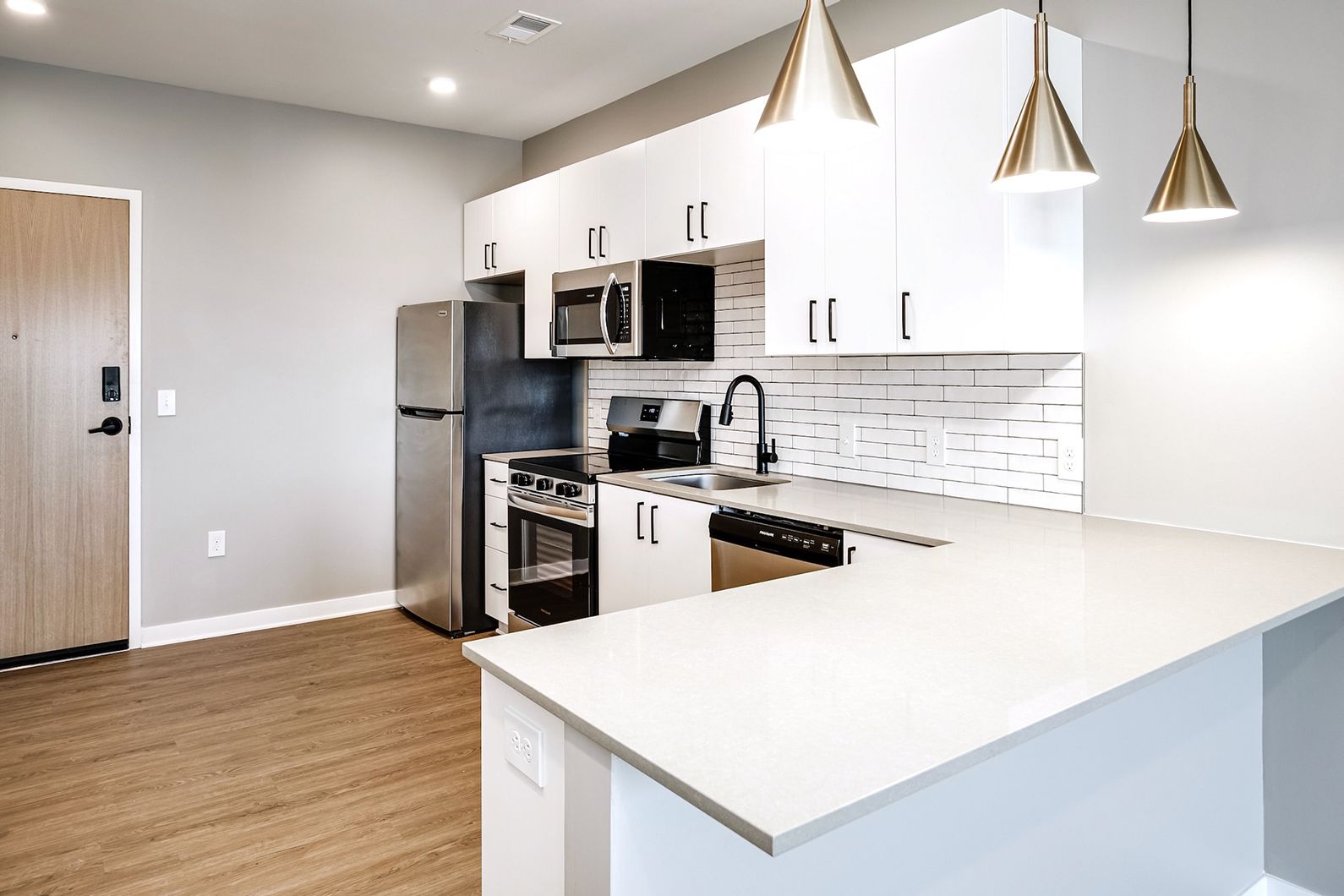 Modern white kitchen with stainless steel appliances, island counter, and pendant lights