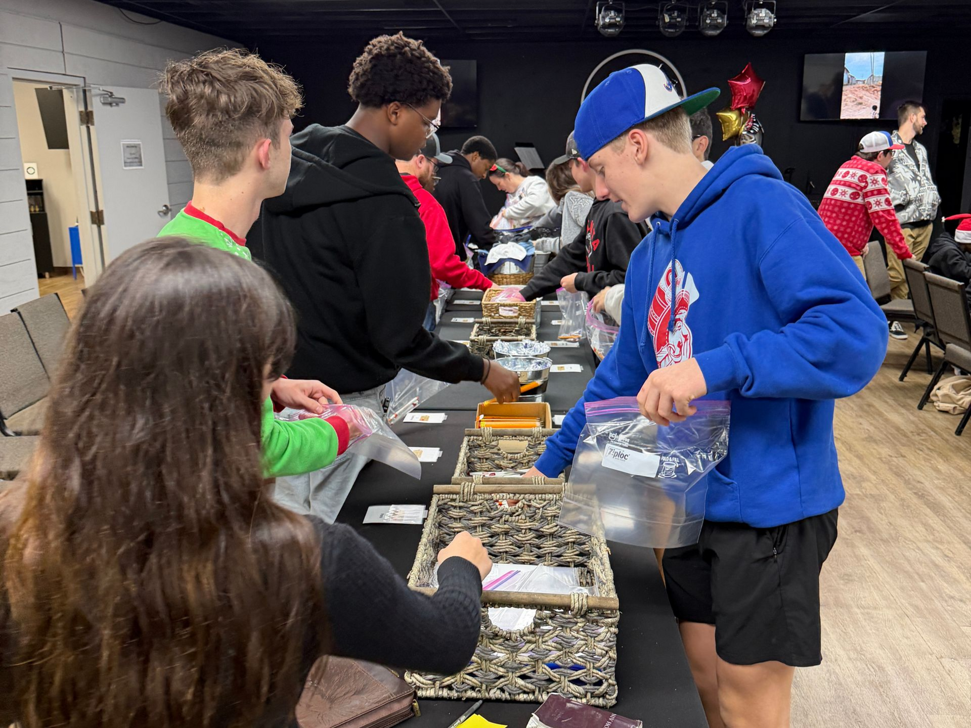 Volunteers packing colorful candy bags at a long table in a community hall