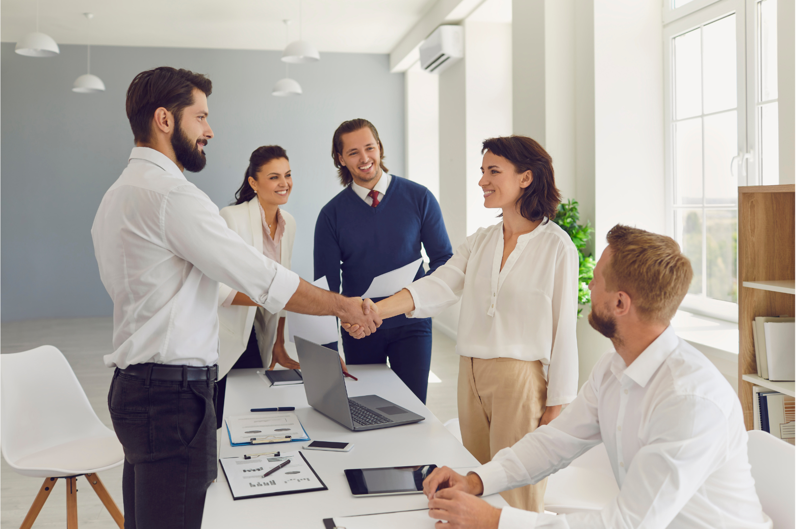 Business colleagues shaking hands in an office, celebrating a deal in regards to HR compliance Texas.