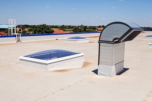 A roof with a lot of skylights and a chimney on it.