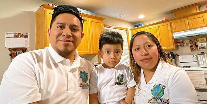 A man , woman and child are posing for a picture in a kitchen.