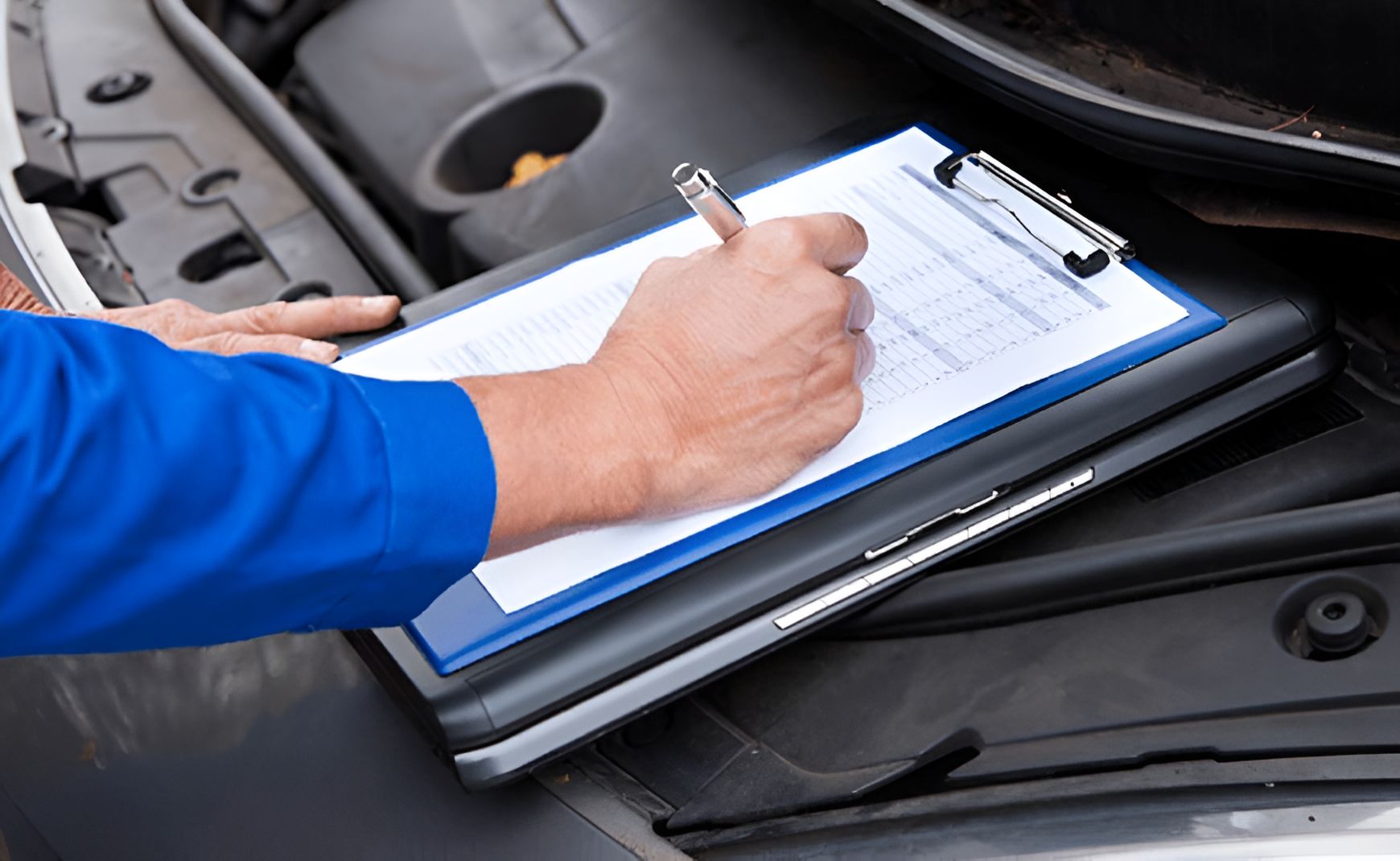 A Person is Writing on a Clipboard Under the Hood of a Car — Blackwall Tyre Service & Mechanical Repairs In Point Clare, NSW
