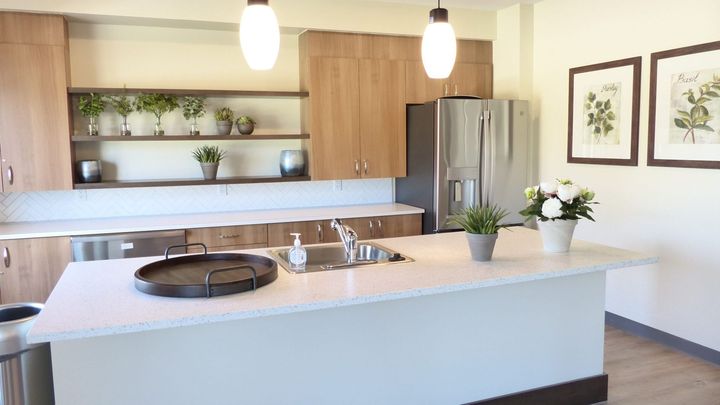 Modern kitchen with white island, wood cabinets, stainless refrigerator, and pendant lights