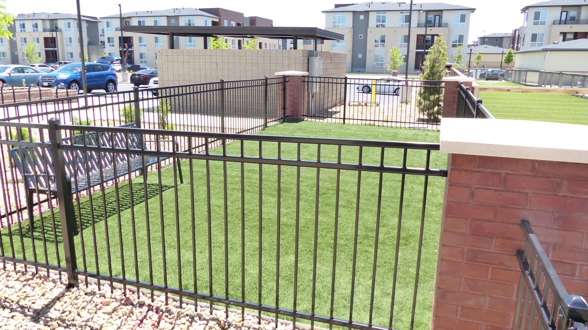 Black metal fence around a grassy courtyard with apartment buildings in the background