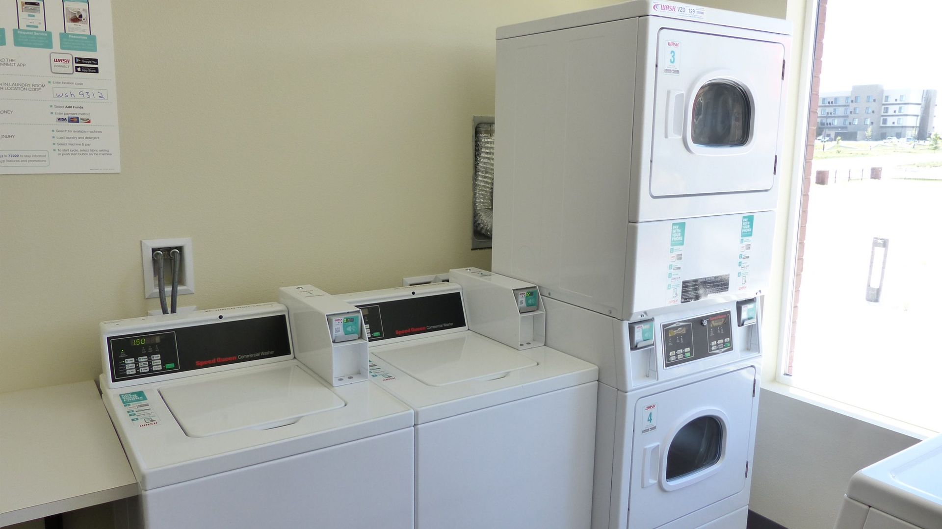 Laundry room with white washers and dryers, including stacked machines near an open door.