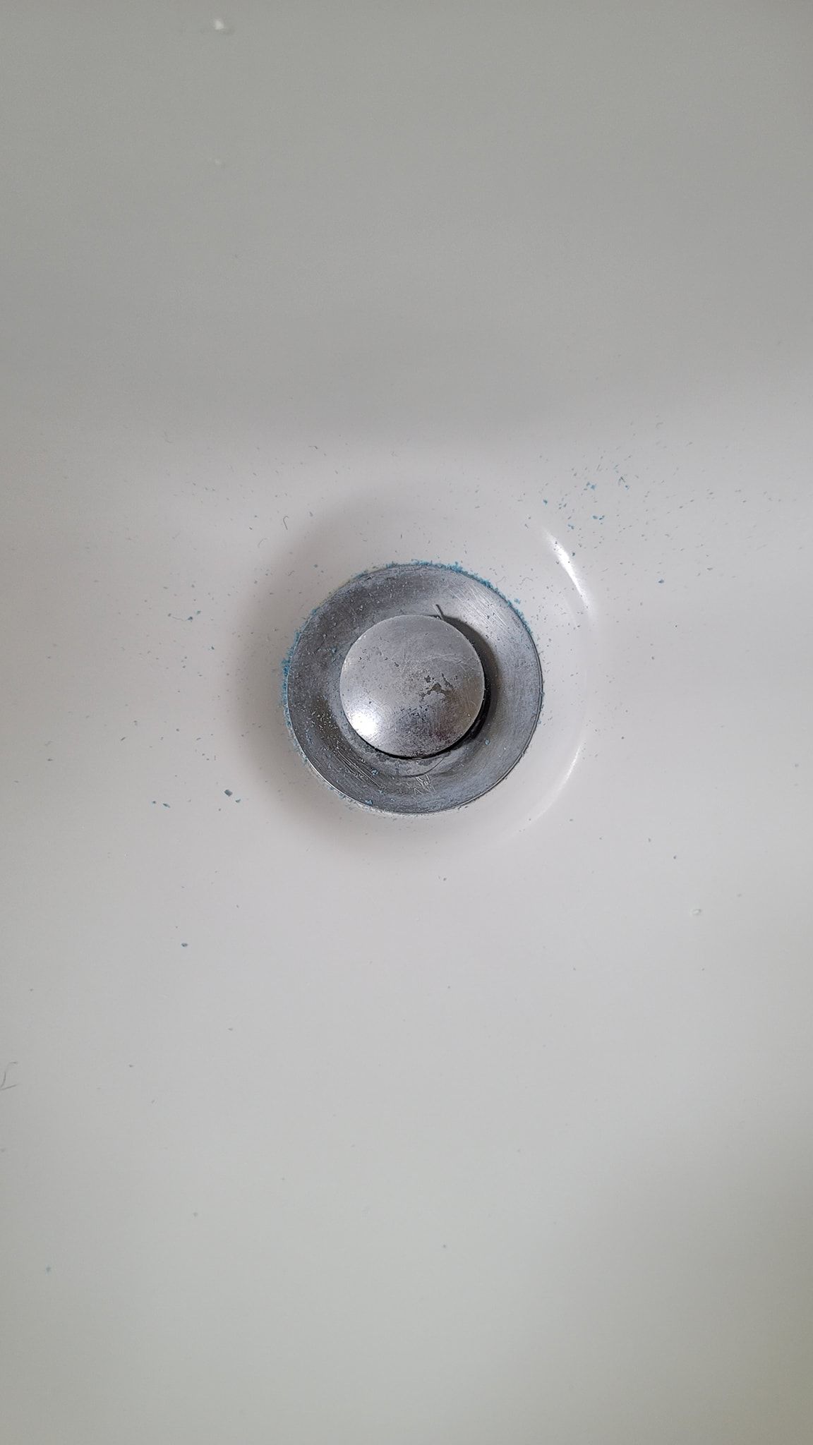 A close up of a clean sink drain on a white sink.