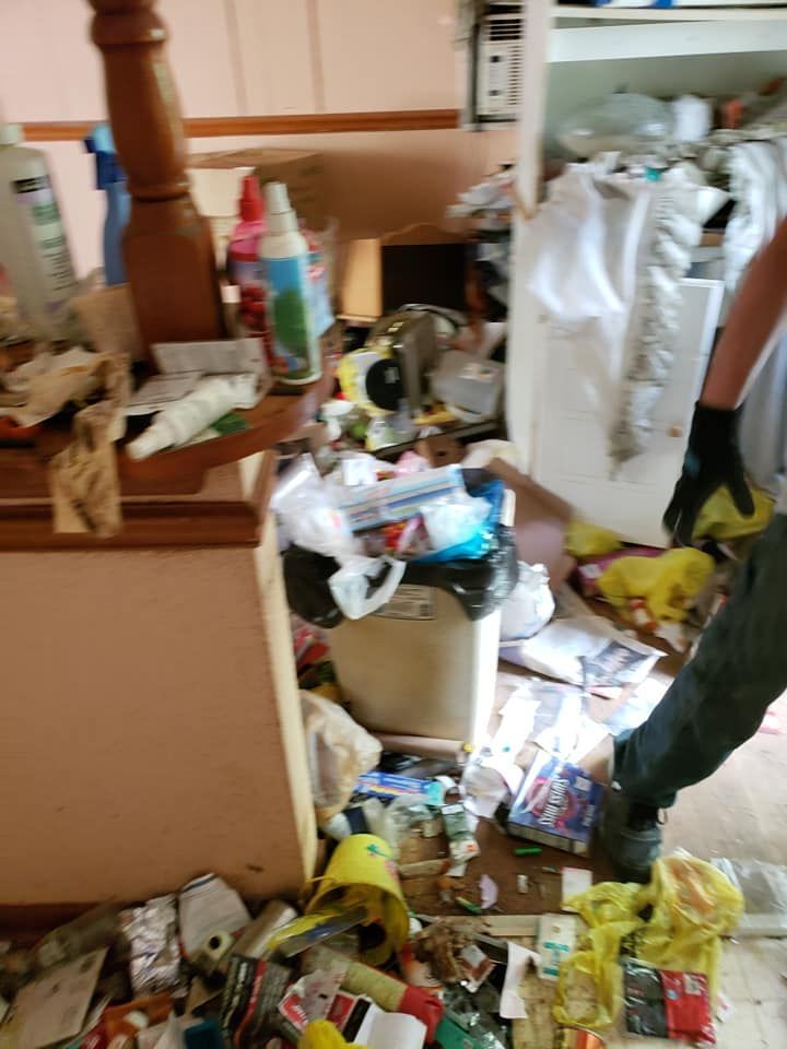 DAG personnel is cleaning in a messy room with a trash can.