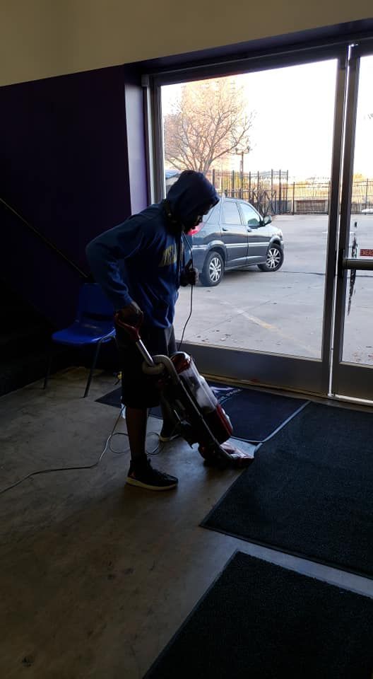 A man is using a vacuum cleaner to clean the floor of a building.