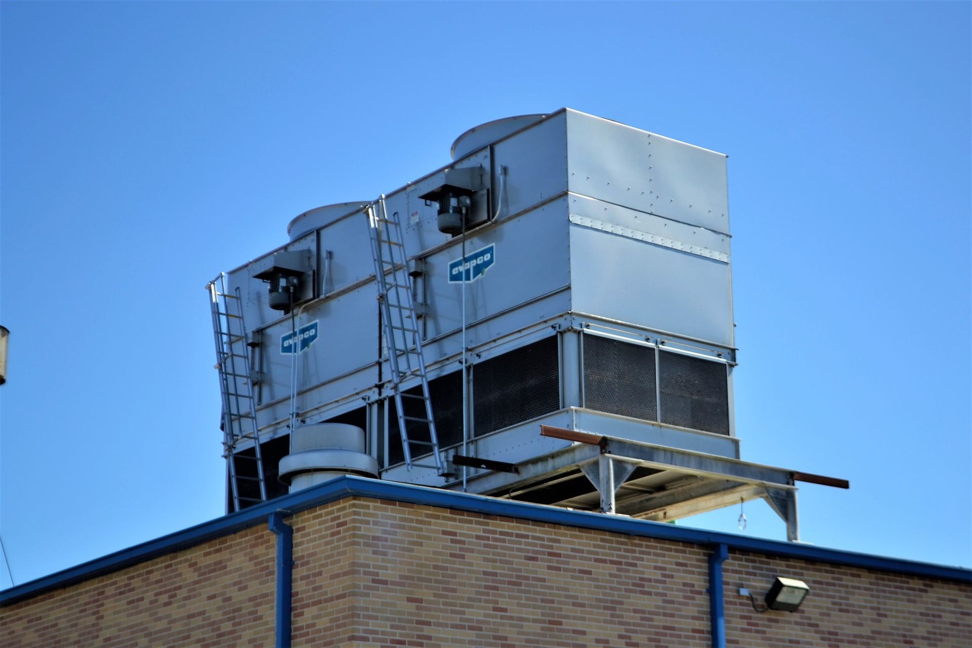 Two cooling towers are sitting on top of a brick building.