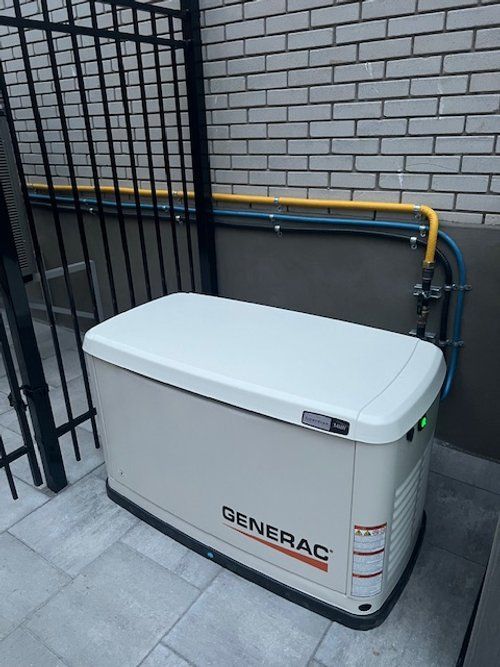 A generator is sitting on the side of a building next to a fence.