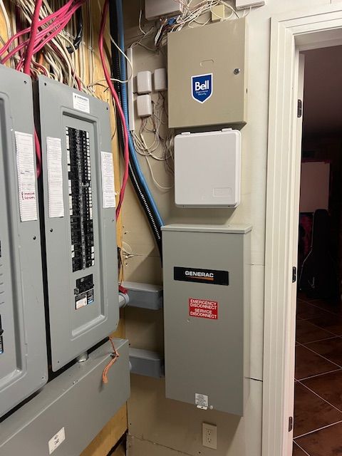 Electrical panels and utility boxes mounted on a wall in a narrow indoor hallway.
