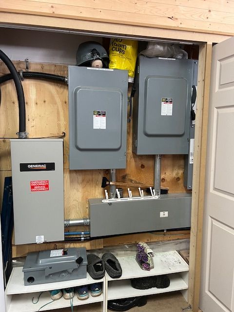 Electrical panels and breaker boxes mounted in a small utility closet with shelves and tools.