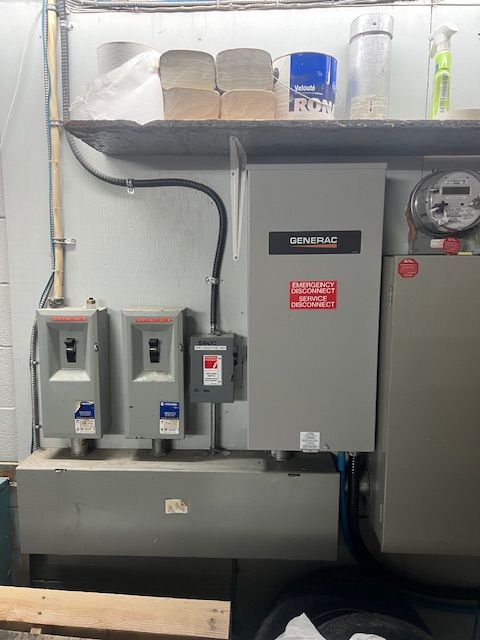 Industrial electrical panel and meters mounted on a wall above a large tank in a utility room