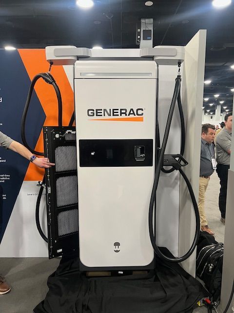 Generac industrial generator display at an indoor trade show, with people nearby